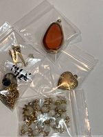 Full view of the jewelry lot showing pendants, earrings, and necklace in plastic bags