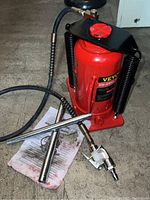 Photo of red VEVOR air bottle jack with two chrome handles, air hose and manual on floor.