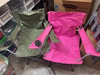 Front side view showing both chairs fully opened side-by-side, displaying cup holders on armrests and metal foldable frames.