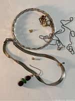 Various jewelry pieces laid out including bracelets, earrings, and chain necklace to show full lot contents.