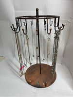 Full view of copper merry go round necklace holder displaying 20 necklaces with various pendants hung on each hook.