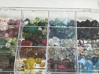 Top view of clear multi-compartment bead holder showing pink, green, yellow, black, clear sized glass beads by color
