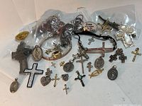 Photo showing a variety of religious crosses, pendants, bracelets, rings, and pins laid out together, made from gold, silver, and other materials.