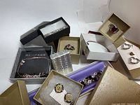 Overview of jewelry pieces in their individual boxes including rings, bracelets, bangles, charms, and earrings.