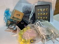 Overview photo showing various prepacked jewelry pieces including rings, bracelets, earrings, and tie clips, mostly contained in small organza bags and boxes.