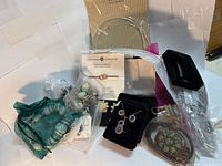 Overall assortment of jewelry items including gift bags, boxes, earrings, bracelet, and decorative pin.