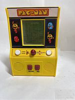 Front view of mini yellow Pac-Man handheld arcade game showing screen with Pac-Man maze, joystick, and buttons.