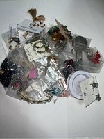 Overview photo showing various jewelry pieces including earrings, rings, beads, and necklaces mostly in plastic bag packaging.