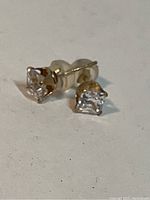 Pair of 10k gold stud earrings with clear cubic zirconia stones viewed from front side.
