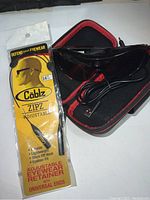 Black Pivothead spy camera glasses with USB cable inside a black and red zippered case. Packaged adjustable eyewear retainer cables labeled 'Cablz Zipz Adjustable'.