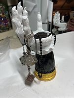 Witches forearm and hand statue adorned with metal dice chain and black pendant necklace