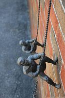 Two metal climbers hanging on brick wall, showing full length and hooks