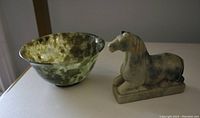 Photo showing both spinach jade bowl and stone horse figurine alongside each other on a flat surface.