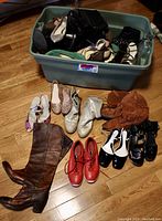 Overview photo of multiple shoes and boots displayed inside a large plastic bin and some arranged on floor, featuring a variety of styles and colors.