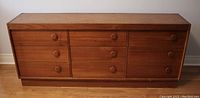 Front view of wood dresser showing nine drawers and knob pull configuration