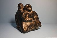 Front view of the vintage Inuit soapstone mother and child carving highlighting the detailed facial features and the child in the mother's arms.
