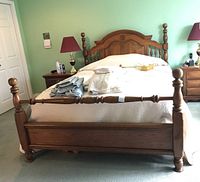 Front view of oak wood bed frame with bedding on carpeted floor