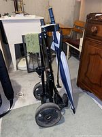 Photo of the black metal Bag Boy golf caddy showing large wheels with Bag Boy logo, adjustable straps and foldable frame.