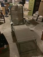 Full view of the folding patio lounger showing frame, seat, backrest, and armrests