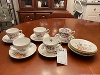 Five teacups with matching saucers and four additional saucers arranged on a table