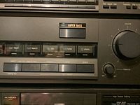 Close-up of front panel showing Super Bass button, input selector buttons and level meters.