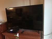 Wide shot of Vizio D55-F2 TV on stand with Panasonic DVD player and remote