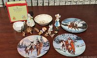 Collection view of figurines including Bunnykins, animal figurines, and multiple decorative plates with winter scenes on horses and Native Americans.