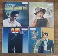 Top-down view of four Elvis Presley vinyl record covers laid out on a flat surface showing front cover artwork for Moody Blue, Paradise Hawaiian Style, Elvis Country, and Frankie and Johnny albums.