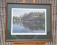 Framed print showing lake, canoes, trees with reflection and wood frame
