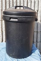 Front view of black Rubbermaid plastic garbage can with lid and integrated handle showing the brand and overall condition.