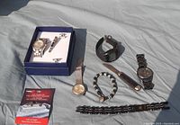 Lot contents with four wristwatches, black and silver braided bracelet with beige beads, knife with wooden handle, and other men's jewelry items.