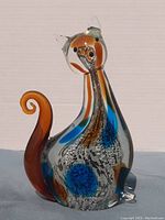 Front view of Murano glass cat figurine showing orange curled tail and colorful internal swirls.