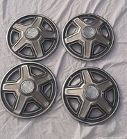 Four original 1969 Ford Mustang hubcaps laid out on a light cloth, showing overall condition and design details.