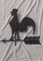 Front view of rustic metal rooster weather vane showing detailed rooster figure and horizontal arrow with pointed ends.