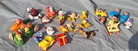 Wide view of all PVC figures arranged on a gray fabric surface showing characters and accessories.