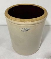 Front view of stoneware crock showing blue crown 8 mark and beige glaze with some discoloration.