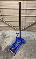 Full view of the blue hydraulic garage jack with the handle extended upward, showing the overall item shape and structure.