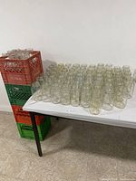 Photo of multiple mason jars arranged on a white table with red and green plastic crates stacked next to it.
