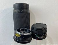 Front view showing Canon 50mm lens, Makinon lens with 'PASSED' sticker, Tokina large zoom lens