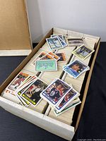 Photo showing stacks of O-Pee-Chee hockey cards in a box, with multiple player cards displayed on top.