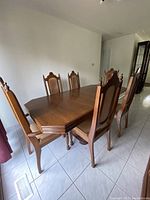 Side angle view showing dining table and chairs with carved wooden frames and upholstered seats.