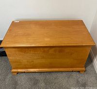 Front view of older Puritan style pine blanket box showing natural wood grain and carved feet.