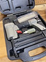 Porter Cable pneumatic brad nailer with oil bottle and pack of brad nails inside plastic carrying case.