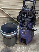 Photo showing the Sinomiz brand blue power washer with hose coiled on top beside a gray Simoniz branded bucket with grid insert inside.