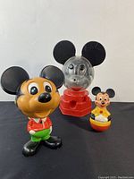 Lot showing three vintage Mickey Mouse themed toys including talking Mickey, gumball machine and roly toy