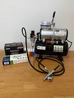 Full view of Timbertech airbrush compressor with hose, airbrush gun, 5 paint bottles, and some boxed paint kits