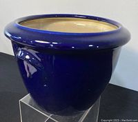 Side angle view showing the round fishbowl shape and glossy deep cobalt blue glaze of the planter with cream interior.