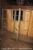 Full view of the antique wooden quilt rack standing, showing three folding panels with horizontal bars for hanging quilts.