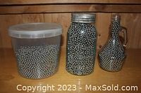 Photo showing three containers filled with 1/4" ball bearings on a wooden surface.