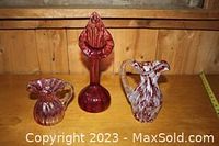 Photo showing all three blown glass items together: small red pitcher, large white and red mottled pitcher, and tall red vase